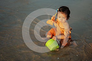 happy toddler baby girl playing toy and water on sea beach