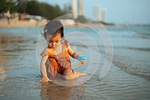 happy toddler baby girl playing toy and water on sea beach