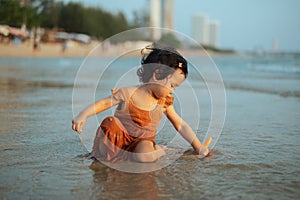happy toddler baby girl playing toy and water on sea beach