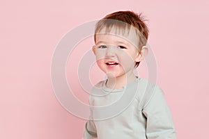 Happy toddler baby on studio pink background, copy space. Emotional