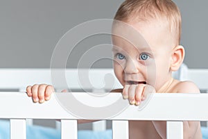 A happy toddler bathing, grabbing for something with a smile, using their finger, nose, eyelash, and gesturing curiously
