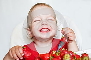 Happy toddler boy eating strawberries
