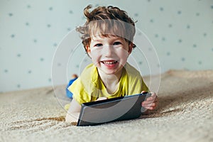 Happy toddler boy having fun playing game on gadget ,Preschool kid sititng on sofa with smiling face watching cartoon on smart pho