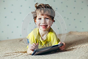 Happy toddler boy having fun playing game on gadget ,Preschool kid sititng on sofa with smiling face watching cartoon on smart pho