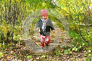 Happy toddler boy running in autumn outdoors