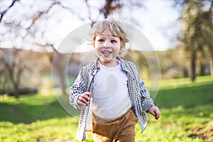 Happy toddler boy running outside in spring nature.