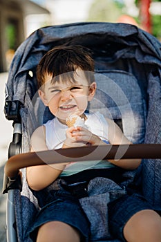 Happy toddler eating ice cream.Messy child eats frozen sweet cone.Kid eating sugar and sweets.Baby diet and unhealthy nutrition.
