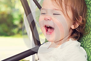 Happy toddler girl laughing while on a swing