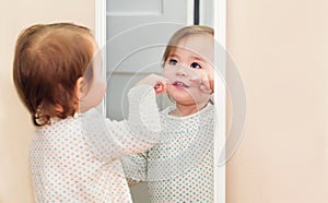 Happy toddler girl looking at herself in the mirror