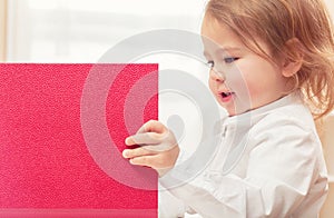 Happy toddler girl opening big red binder