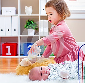 Happy toddler girl playing with her baby sibling