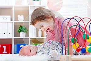 Happy toddler girl playing with her baby sibling