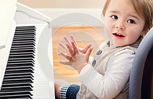 Happy toddler girl playing piano