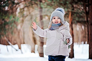 Happy toddler girl playing in winter forest with snow