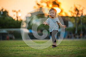 happy toddler girl running on grass field in park at sunset