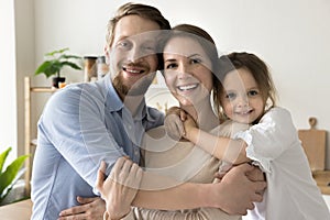 Happy toddler kid and dad embracing cheerful mom with love