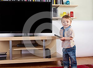 Happy toddler with remote control in front of the TV