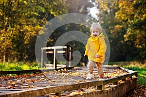 Happy toddler run in autumn park wear yellow coat