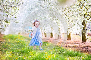 Happy toddlger girl in fairy costume in blooming garden