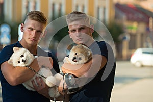 Always happy together. Muscular men with dog pets. Happy family on walk. Twins men hold pedigree dogs. Happy twins with