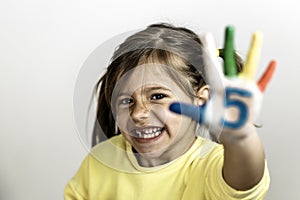 Happy toothless little girl with the five number painted on the hand laughing and having fun - Little girl who is painting her