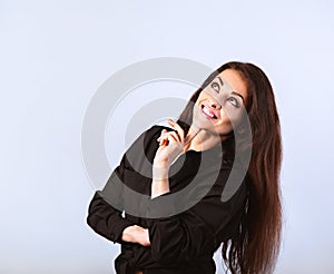 Happy toothy thinking smiling brunette woman looking up in black shirt with hand under the face on blue background with empty