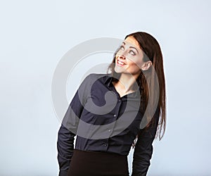 Happy toothy thinking smiling business woman looking up in blue shirt on blue background with empty copy space. Closeup