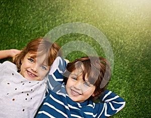 Happy, top view and portrait of kids on grass for relaxing, bonding and happiness in garden. Family, nature and above of