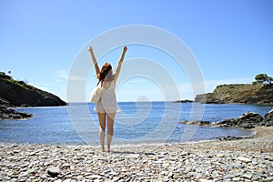 Happy tourist on the beach celebrating vacation raising arms