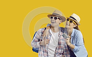 Happy tourist couple in holiday hats and sunglasses on yellow copy space background