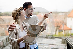 Happy tourist couple with map traveling outdoors