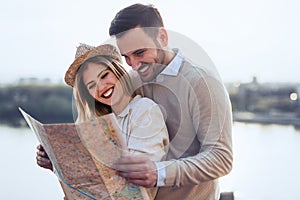 Happy tourist couple with map traveling outdoors