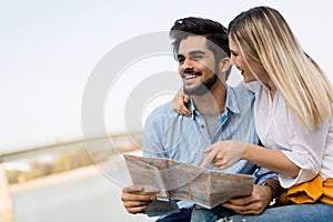 Happy tourist couple with map traveling outdoors