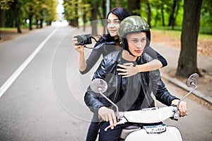 Happy tourist young couple on scooter ride in new city. Woman making photo on camera while riding outdoors