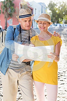 Happy tourist couple using map in the city