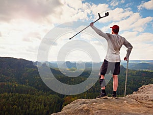 Happy tourist with forearm crutch above head achieved mountain peak. Hiker with broken knee in immobilizer