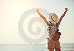 Happy tourist girl with backpack and hat on sea