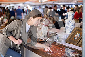 Happy tourist girl looking at jewelry sold at flea market
