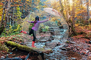 Happy tourist girl in rubber boots with umbrela in the forest