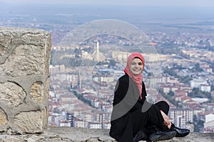 Happy tourist girl sitting on the ruins of Afyon castle photo