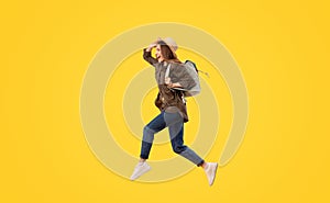 Happy Tourist Lady With Backpack Jumping Over Yellow Background