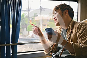 Happy tourist man looking through the window while commuting by bus