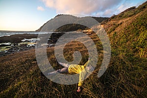 Happy tourist man lying down and having rest on ocean trail near mountains at sunset time