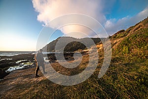 Happy tourist man walk and hike on ocean trail near mountains at sunset time