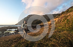 Happy tourist man walk and hike on ocean trail near mountains at sunset time