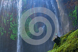 A happy tourist man watching Sewu Waterfall. The biggest waterfall in Java Island. Nature landscape background of travel trip and