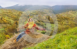 Happy tourist sitting in hay in autumn