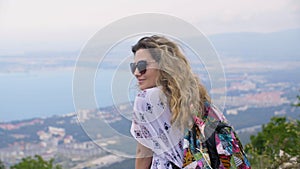 Happy tourist woman on mountain top admiring seascape. Smiling woman enjoying beautiful landscape to resort city from