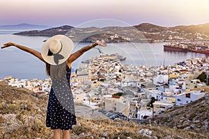 A happy tourist woman overlooks the city of Ermoupoli, Syros island