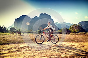 Happy tourist woman riding a bicycle in mountain area in Laos. T